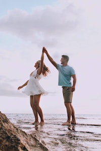 a couple holding hands in the water at the beach