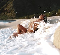 a woman in a bikini laying on the beach