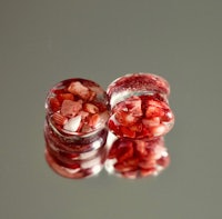 a pair of red and white glass plugs on a surface