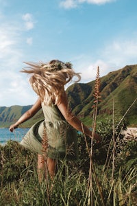 a woman in a green dress with her hair blowing in the wind