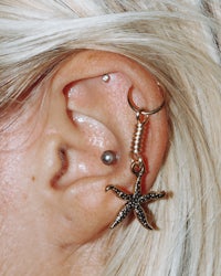 a woman's ear with a starfish ear cuff